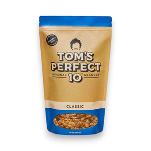 A beige and blue resealable pouch labeled "TOM'S PERFECT 10 - CLASSIC GRANOLA," featuring a transparent window at the bottom displaying the granola inside mixed with cherries. The pouch weighs 10 ounces (283.5 grams). A circular label says "Original Formula.