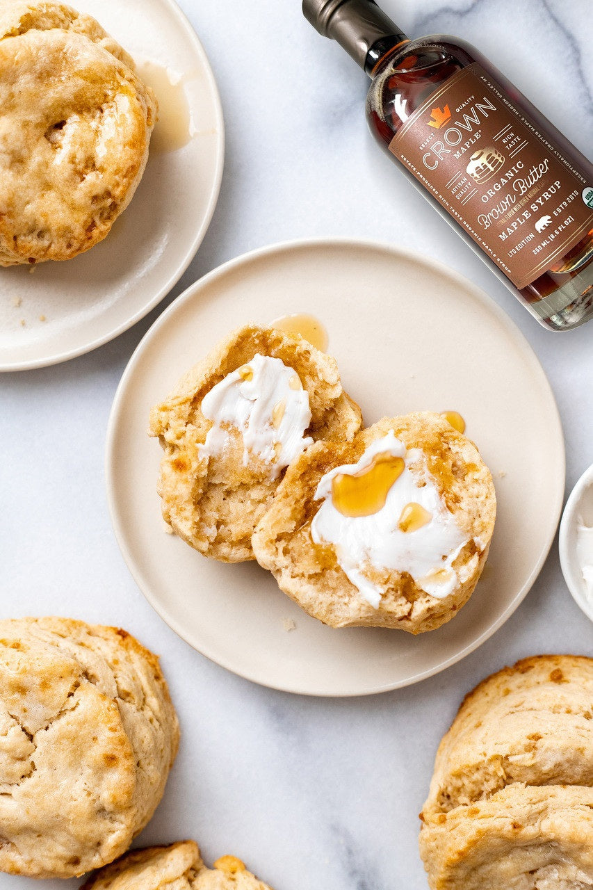 A bottle of CROWN MAPLE - BROWN BUTTER ORGANIC MAPLE SYRUP from the CROWN MAPLE brand, featuring a brown label with a gold cap, product details, and an organic certification badge.