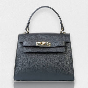 The LE BORSETTE LEATHER SATCHEL BAG is a small, structured satchel-shaped handbag in light pink, featuring a gold clasp at the front. It boasts a single top handle, an adjustable shoulder strap, and two gold-tone hardware pieces on either side of the handle. The textured leather adds to its luxurious and elegant appearance against the plain white background.