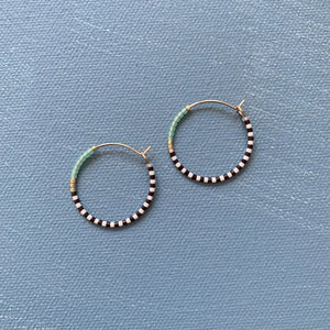 The ALICE RISE MIDI COLORLOOP EARRINGS IN SERRATA feature 14k gold filled hoops with alternating black and white beads, light blue Japanese glass beads, and gold accents—an ideal handmade jewelry piece from ALICE RISE.