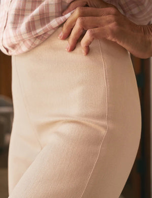A woman with long hair stands indoors, hands on hips, wearing FRANK & EILEEN's WESTPORT ILLUSION WIDE LEG PULL-ON PANT in Champagne Glitter and white sneakers, facing away from the camera in a bright, spacious room.