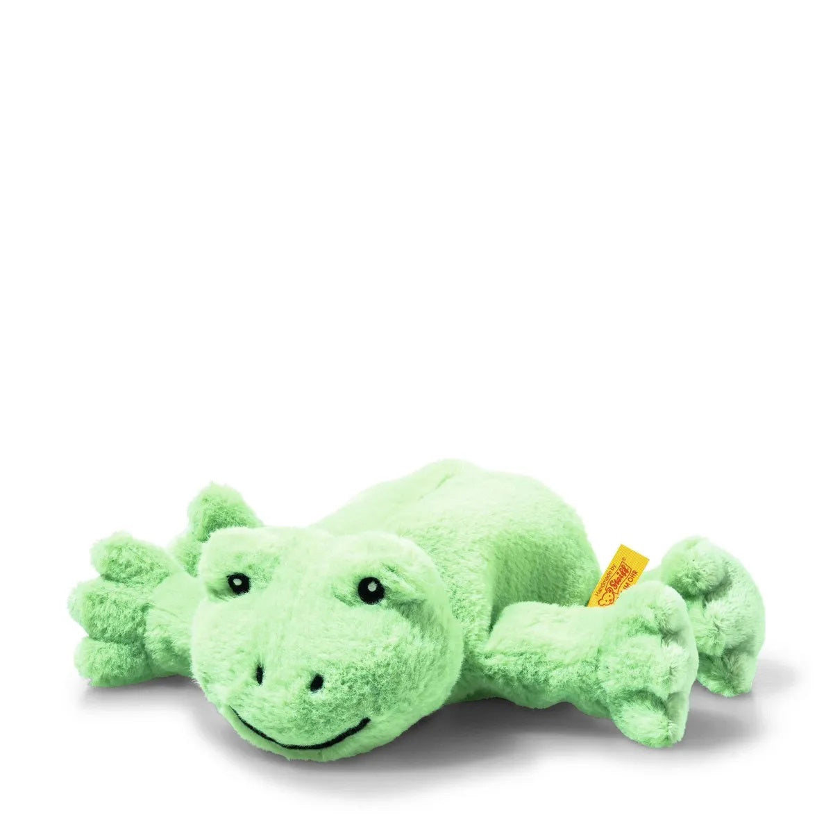 A STEIFF FLOPPY CAPPY FROG plush toy with bright green fur lies on a white background, featuring a smiling face, outstretched limbs with subtle texture, and a small yellow tag on the left side.