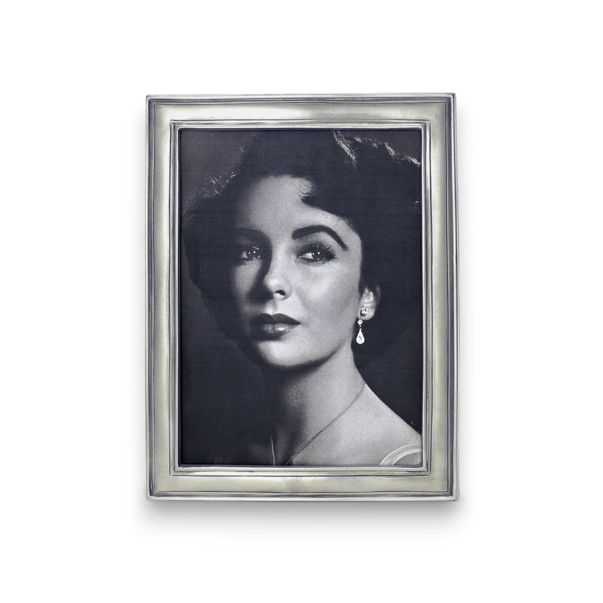 A black-and-white portrait of a woman with dark hair in soft waves, wearing drop earrings and a light top, displayed in the MATCH - LUGANO Rectangular Pewter Photo Frame by MATCH—a refined choice for personalized gifts.