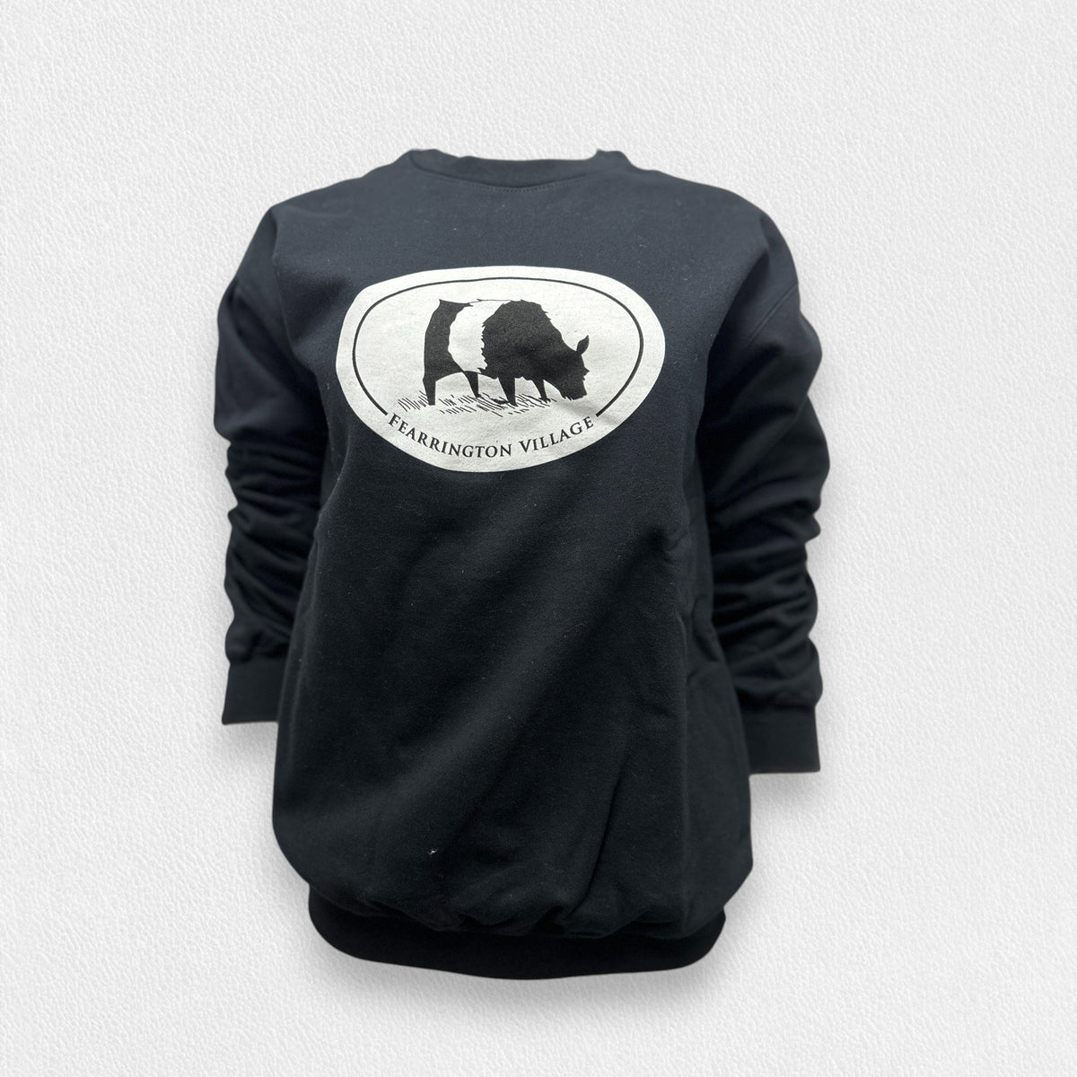 The GILDAN FEARRINGTON LIFESTYLE COLLECTION - FEARRINGTON BELTIE COW SWEATSHIRT in black triblend features a silhouetted figure of a goat within an oval frame, with the text &quot;Fearrington Village&quot; below the image. The unisex tee is displayed against a plain, light gray background.