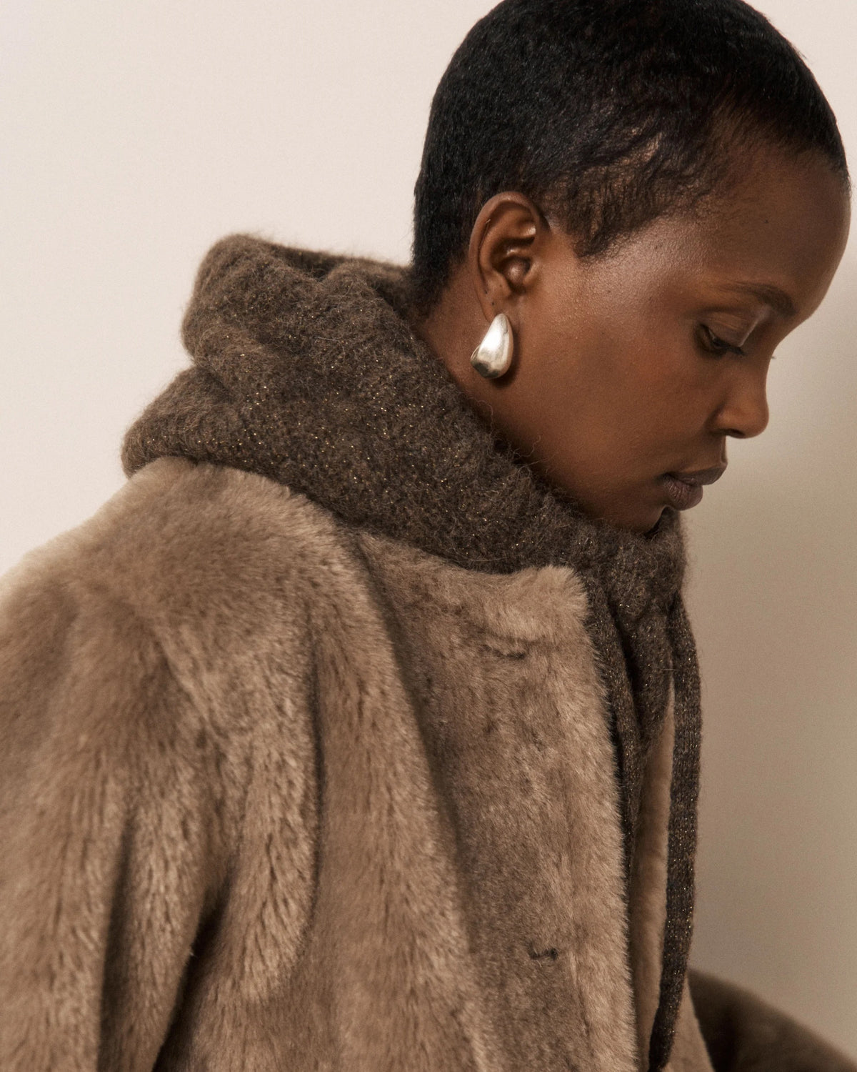 Wearing the HARTFORD MEVA Hood in Chocolate, a person gazes seriously at the camera against a plain background.