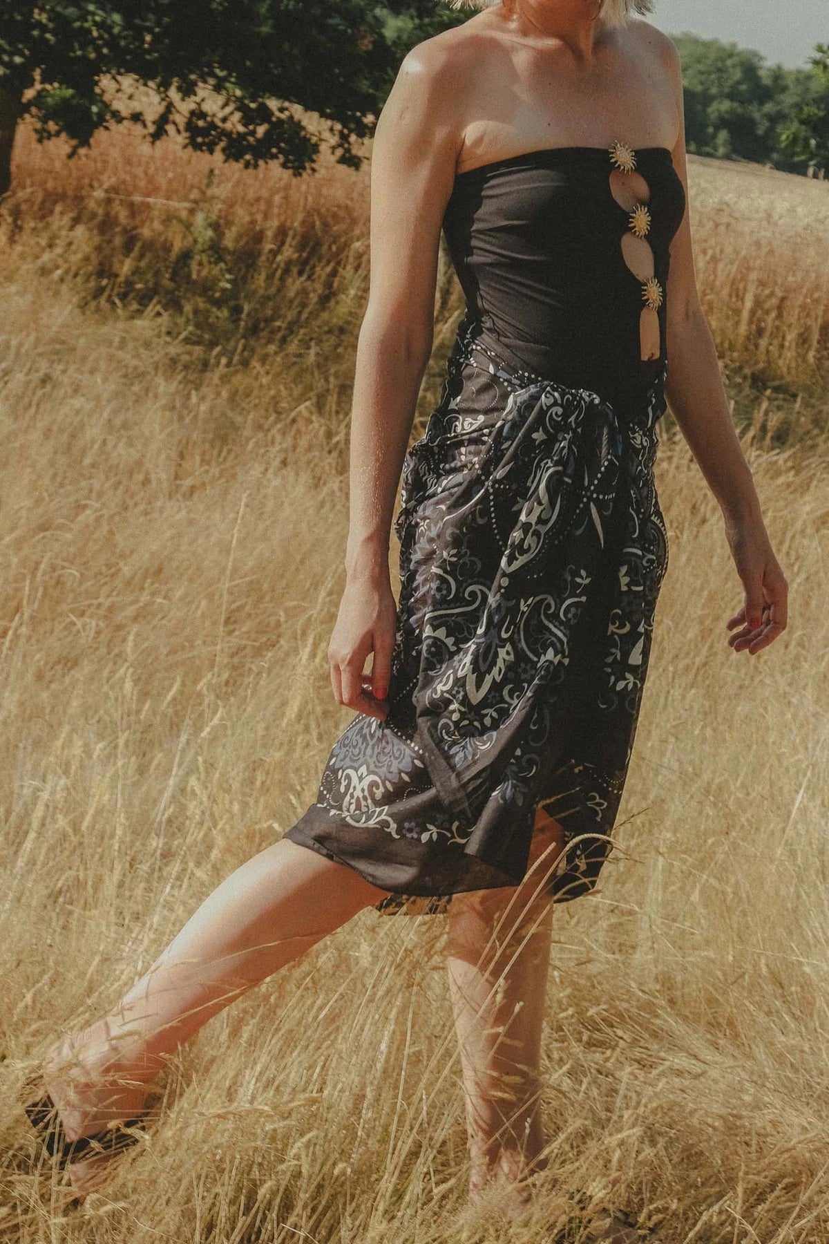 The MAISON LECOMTE - COSTA BRAVA BLACK SARONG by MAISON LECOMTE FLAMENT, featuring a white and blue paisley pattern, is tied in a loose knot against a plain white background.