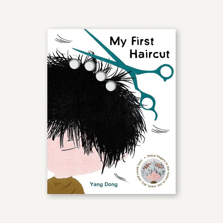 The cover of MY FIRST HAIRCUT BOOK by PETITECOLLAGE showcases a cartoon child with a messy, overgrown hairstyle and large blue scissors ready to cut the hair. This interactive board book includes tactile buttons for play, making it an ideal gift for parents and toddlers approaching the first haircut milestone.