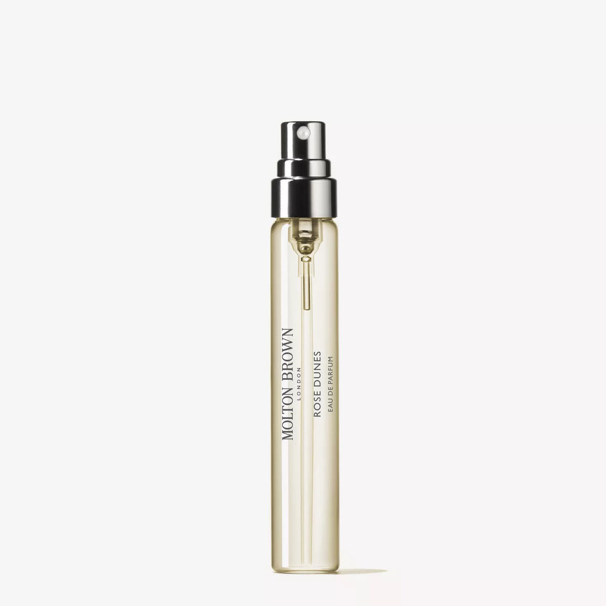 An upright, clear glass bottle of MOLTON BROWN - ROSE DUNES EAU DE PARFUM stands against a plain white background. It features a silver spray nozzle and minimalist label, reflecting the fragrance’s refined character.