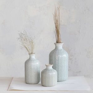Close-up of the GRAY EMBOSSED STONEWARE VASE, SMALL by CREATIVE COOP reveals a repeating, symmetrical pattern resembling interwoven green and beige threads—much like knitted fabric or stylized leaf motifs.
