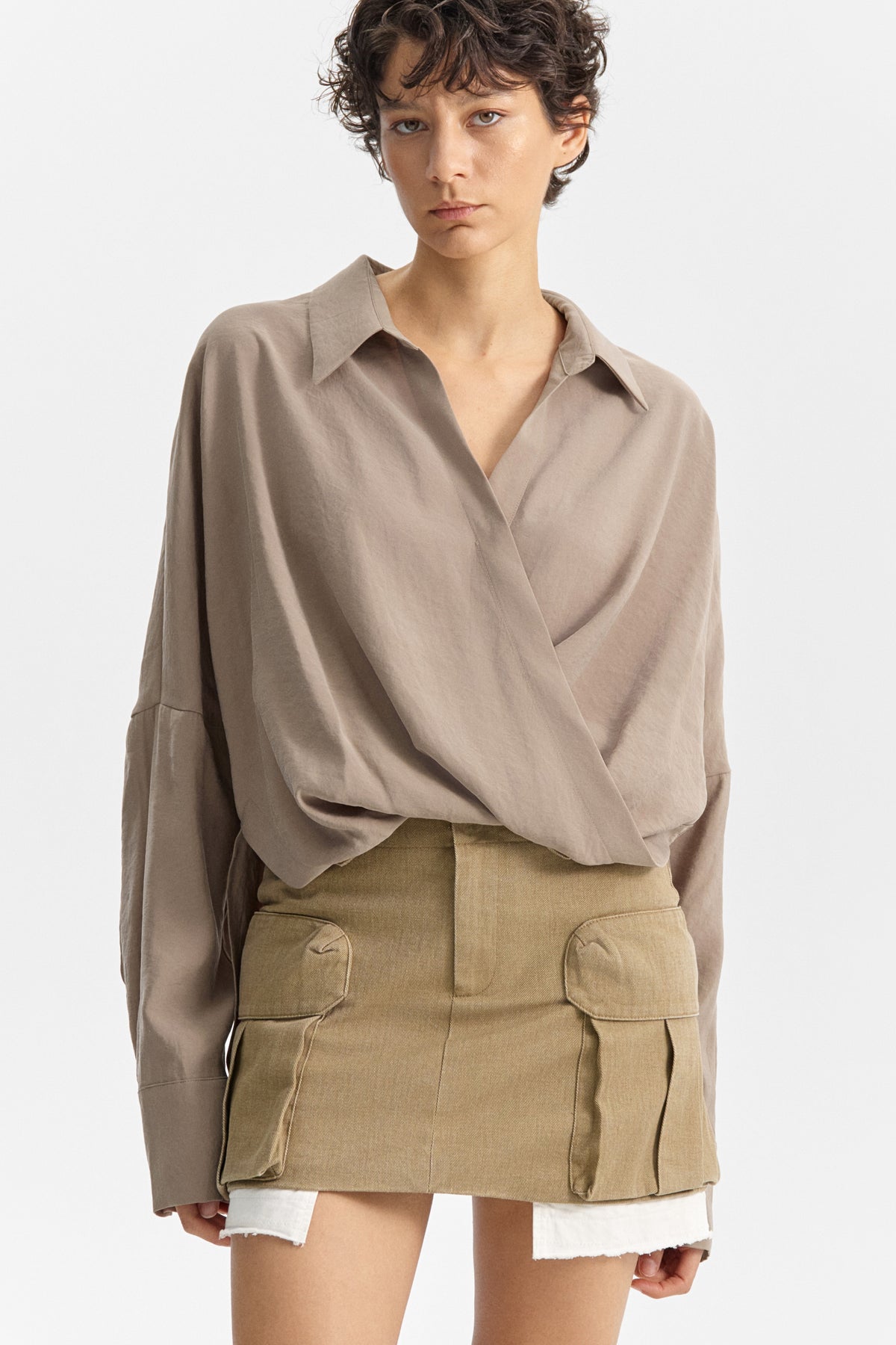 The ELEH - DRAPE FRONT BLOUSE by ELEH is a taupe Italian cotton top with a draped crossover front, wide cuffs, and a loose fit, shown against a plain white background.