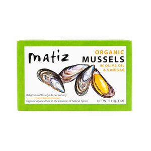 A green rectangular box labeled "MATIZ - MUSSELS IN ORGANIC OLIVE OIL" from MATIZ ESPANA. The box features illustrations of three mussels, one of which is open to show the yellow inside. It also notes "0.8 grams of Omega-3s per serving" and weighs 111g (4 oz).