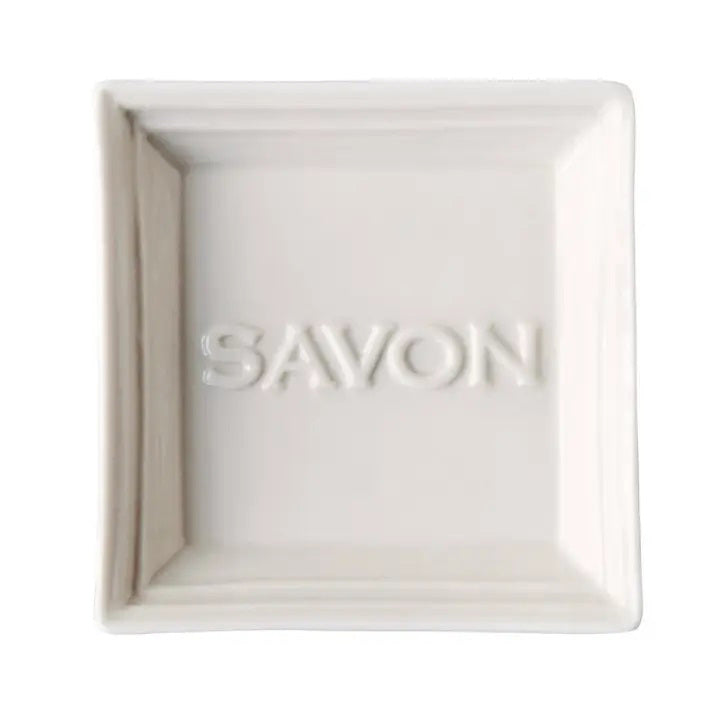 A white, square-shaped CERAMIC SOAP DISH from EUROPEAN SOAPS, LLC featuring raised edges and the word &quot;SAVON&quot; embossed in the center. The design is minimalist and clean, with a smooth surface and a slightly glossy finish.