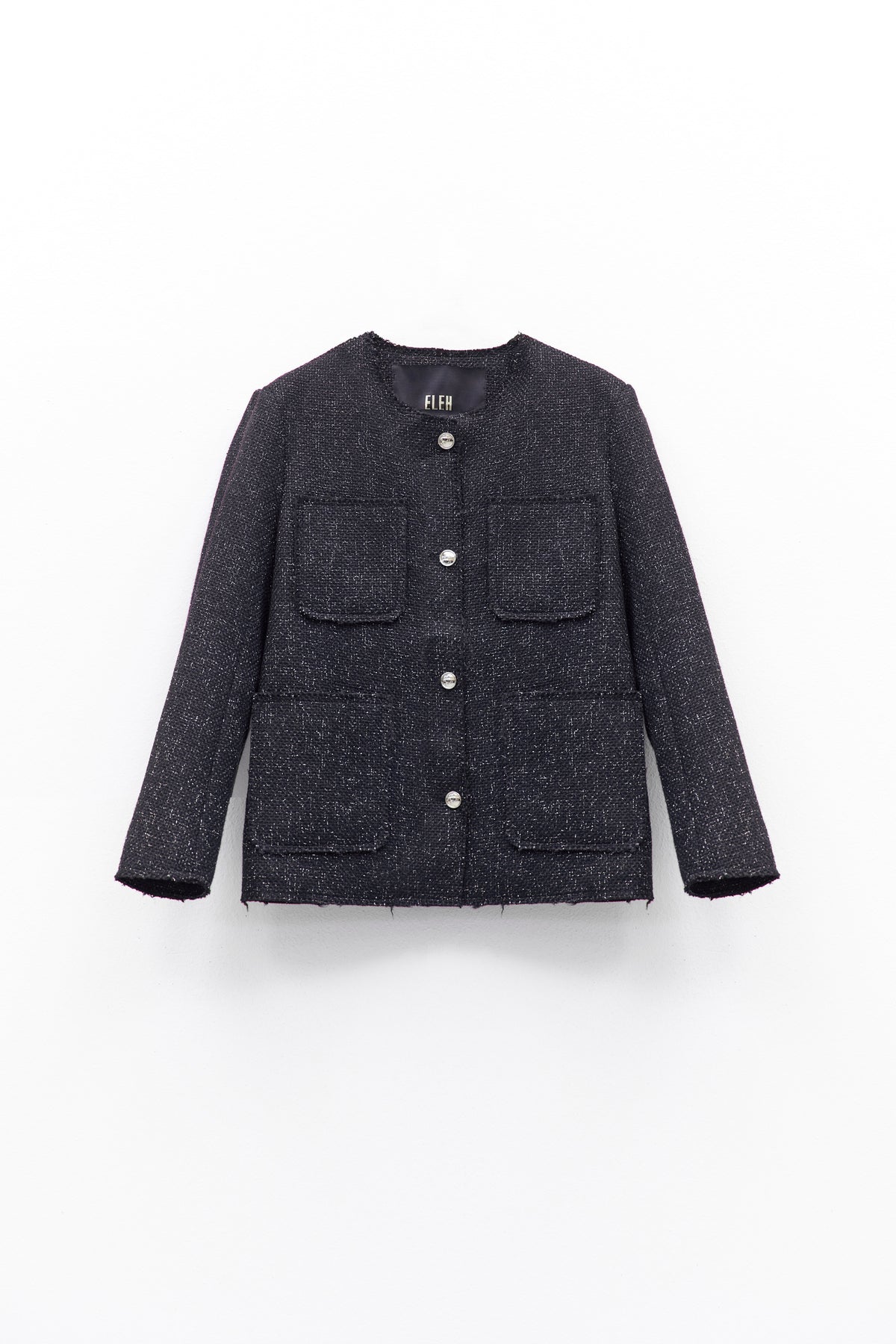 A person wears the ELEH - TWEED JACKET by ELEH, featuring textured black fabric and large front pockets, paired with dark pants and a black clutch with silver chain, against a white background.