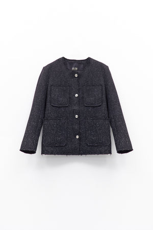 A person wears the ELEH - TWEED JACKET by ELEH, featuring textured black fabric and large front pockets, paired with dark pants and a black clutch with silver chain, against a white background.