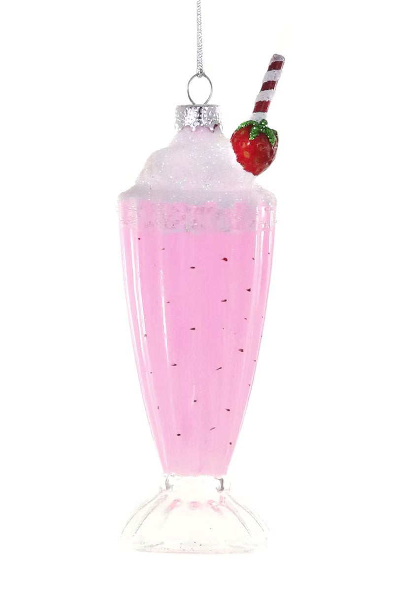The STRAWBERRY MILKSHAKE ORNAMENT by CODY FOSTER features a pink milkshake in a tall glass, topped with whipped cream, a glittery red strawberry, a red-and-white striped straw, and a silver hanging loop.