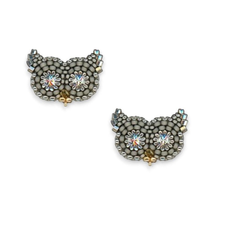 Introducing the MIGUEL ASES - OWL STUD EARRINGS WITH SWAROVSKI CRYSTAL from MIGUEL ASES, INC. These handcrafted earrings feature an intricate design made from grey metallic beads for the body and ears, accented with sparkling rhinestones for the eyes. Made in America, these whimsical and stylish accessories beautifully complement any outfit.
