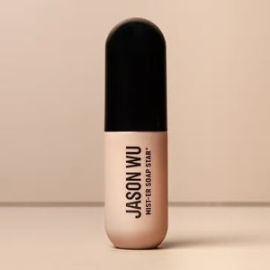 A beige and black cylindrical bottle of JASON WU BEAUTY's "MIST-ER SOAP STAR BROW SOAP" is centered against a neutral background. The minimalistic design features black text on the front, enhancing its sleek aesthetic.