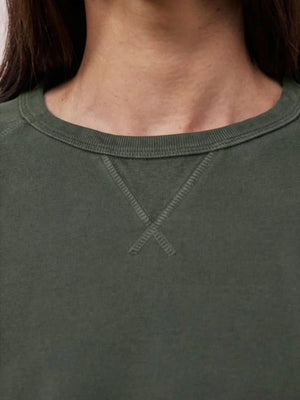 A person with long straight brown hair wears the HARTFORD - LIGHT FLEECE SWEATSHIRT IN ZINC, looking directly at the camera with a neutral expression against a plain light background.