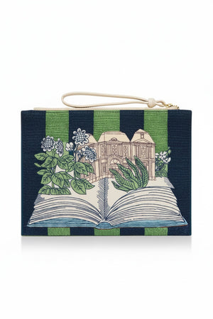 The INOUI EDITIONS - PARIS 7TH ARRONDISSMENT POUCH by INOUI is a rectangular Italian leather pouch with green and navy stripes, an illustrated open book with flowers and a building, plus a white zipper and wrist strap.