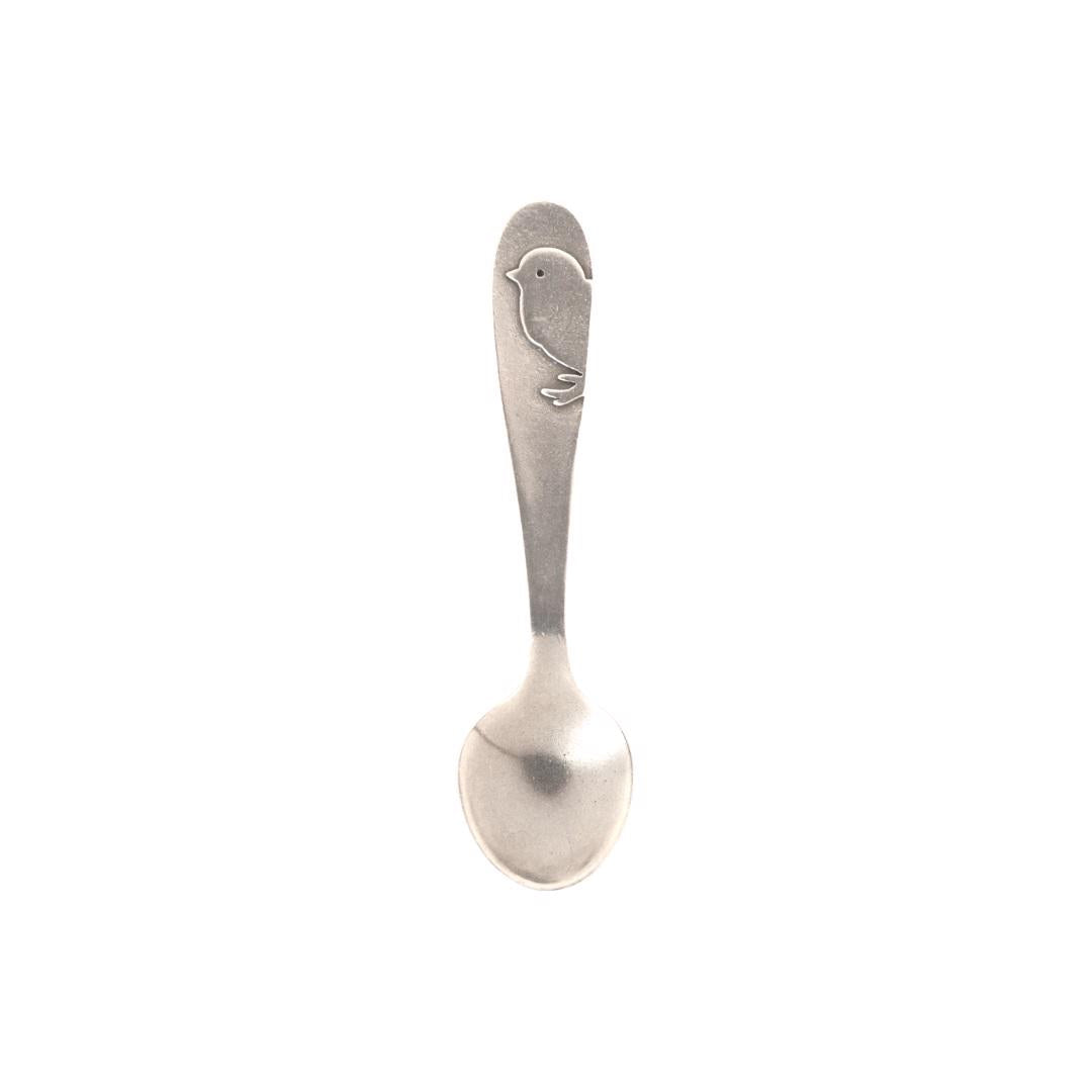 This heirloom quality keepsake, the PEWTER BABY SPOON CHICK from BEEHIVE HANDMADE, is a small, silver-toned spoon with a rounded bowl and an engraved bird design on the handle. Perfect as a vintage-inspired baby spoon, it's presented against a plain white background.