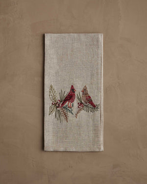A CORAL & TUSK CHRISTMAS CARDINALS LINEN TEA TOWEL made of embroidered natural flax fiber featuring two cardinals perched on pine branches with berries.