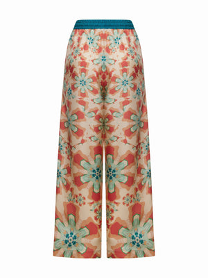 FRANCO FERRARI's ALOE SILK TROUSER is high-waisted with a wide-leg cut, showcasing a resort-style floral print in vibrant orange, teal, and pink on a light background with large blossoms for an eye-catching look.