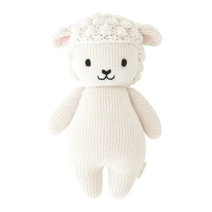 Introducing the CUDDLE + KIND - HANDMADE BABY LAMB by CUDDLE &amp; KIND. This delightful knitted stuffed toy is crafted from 100% cotton yarn and features a white, wool-like texture. It has adorable black eyes, a smiling mouth, and small round ears. The toy’s body boasts a simple design with a smooth and plush finish. Perfect as one of your fair trade baby gifts!