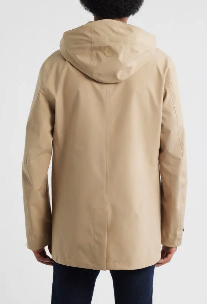 A person wears the SAVE THE DUCK BENJAMIN Hooded Raincoat in Stardust Beige as a button-up coat over a white t-shirt and dark pants, with one hand in their pocket. The person's face is not visible.