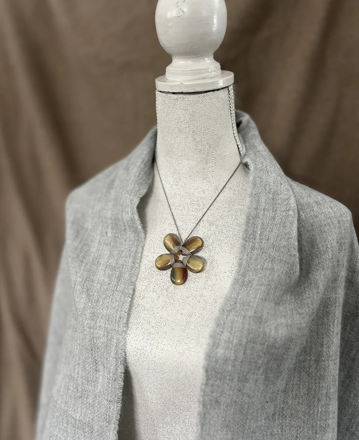 The ANN LIGHTFOOT - FLOURITE FLOWER NECKLACE by ANN LIGHTFOOT showcases a delicate blossom-shaped pendant with five oval, translucent fluorite stones forming the petals and detailed wire wrapping in the center. Suspended from a slim chain against a white background, this elegant piece makes a refined statement for any occasion.