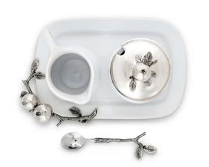 The VAGABOND HOUSE POMEGRANITE CREAMER SET includes a white ceramic sugar bowl with a metallic lid featuring pewter pomegranates, a matching cream pitcher, and a silver spoon with branch-like handle and pomegranate accents on a rectangular tray.