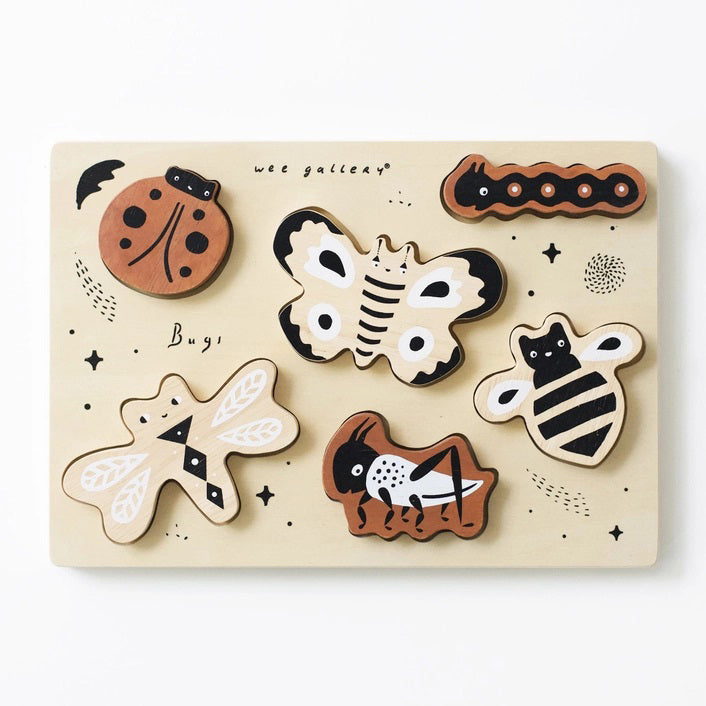 The BUGS TRAY PUZZLE by WEE GALLERY is a wooden puzzle set on a light background, showcasing six insect pieces: a ladybug, a caterpillar, a moth, a bee, a cricket, and a dragonfly. This educational fun bugs set also includes small black stars and the word "Bugs!" emblazoned on the puzzle board.