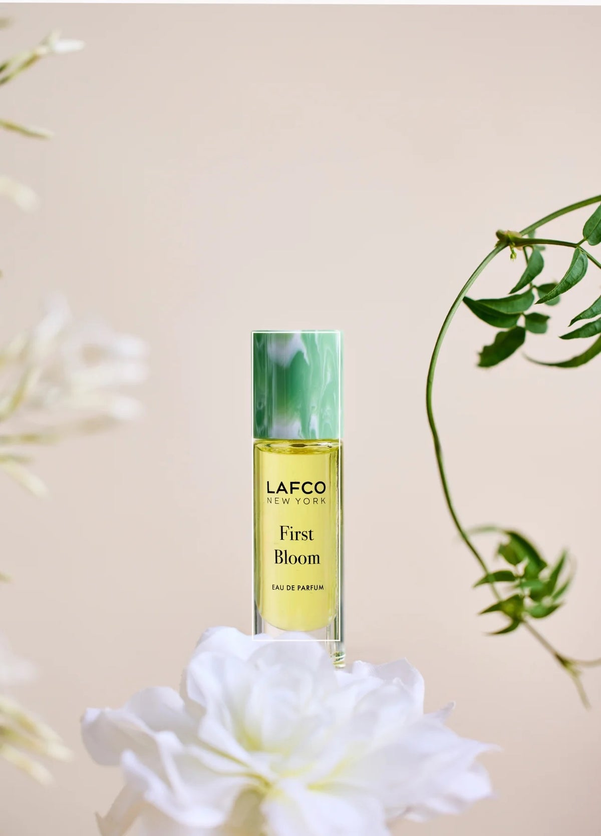A 10ml bottle of LAFCO Fine Fragrance, First Bloom, a vegan eau de parfum that captures the freshness of spring with luminous neroli and radiant floral notes. Presented by LAFCO, this scent features a marbled green and white cap atop vibrant yellow liquid.