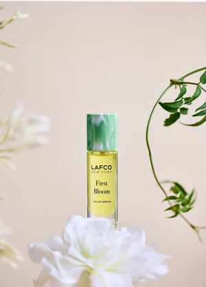 A 10ml bottle of LAFCO Fine Fragrance, First Bloom, a vegan eau de parfum that captures the freshness of spring with luminous neroli and radiant floral notes. Presented by LAFCO, this scent features a marbled green and white cap atop vibrant yellow liquid.
