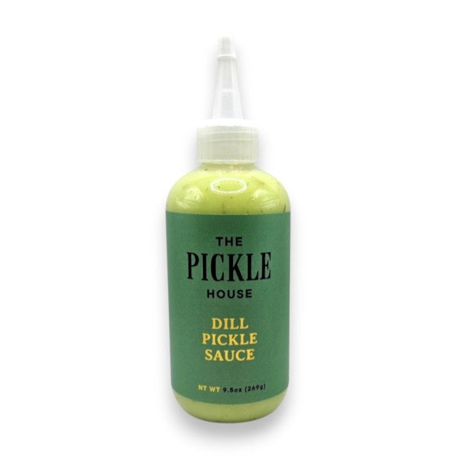 A plastic squeeze bottle featuring a green label with “THE PICKLE HOUSE - DILL PICKLE SAUCE” stands against a lightly textured backdrop—ideal as a tangy marinade or bold salad dressing from THE PICKLE HOUSE for your favorite recipes.