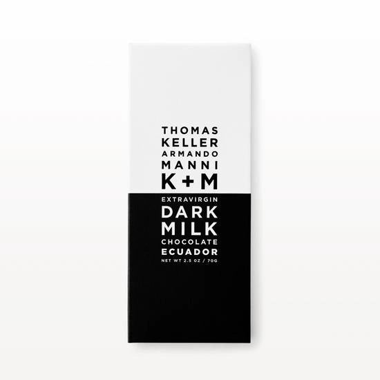 A minimalist chocolate bar packaging featuring a white top half and a black bottom half. Text reads: "K &amp; M EXTRAVIRGIN CHOCOLATE K+M - EXTRAVIRGIN DARK MILK ECUADOR BAR, RICH IN ANTIOXIDANTS. NET WT. 2.5 OZ / 70G.