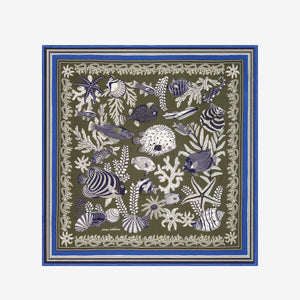 The INOUI EDITIONS - NEPTUNE SCARF IN KHAKI by INOUI features an intricate underwater scene with fish, seaweed, and coral in blue, white, and purple, bordered by geometric blue and green patterns.