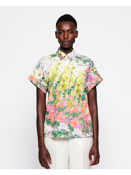 Against a plain white background, someone with short hair wears light-colored pants and the vibrant MIRTO 1956 - Brushstroke Print Cotton Shirt, showcasing its colorful floral and brushstroke design.