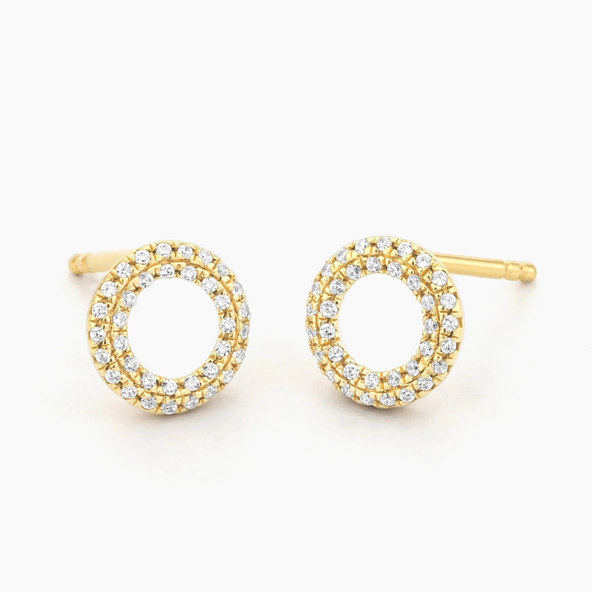 ELLA STEIN - SEALED WITH A KISS STUD EARRINGS by ELLA STEIN, featuring a circular open hoop design with gold plating and two rows of small white gemstones, displayed on a plain white background.