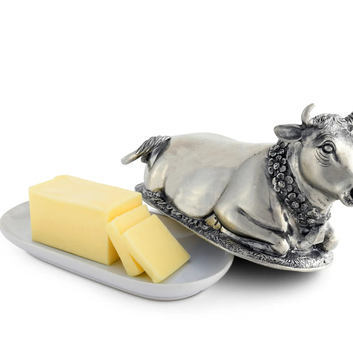 The VAGABOND HOUSE Mabel Cow Butter Dish, by VAGABOND HOUSE, is a silver-toned luxury pewter piece with intricate details. The cow’s textured features and elegant oval base highlight its exquisite craftsmanship.