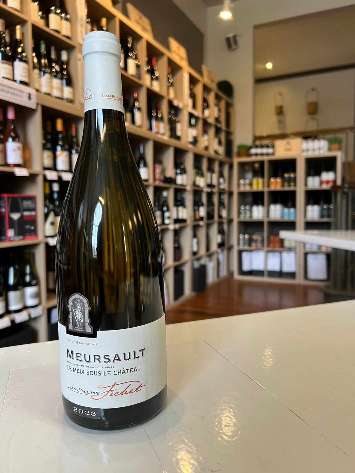 A bottle of JEAN-PHILIPPE FICHET ‘LE MEIX SOUS CHÂTEAU’ MEURSAULT 2023 from WINE: ADVINTAGE, a Burgundy white wine with a white top and clean white label featuring stylish black and red text.