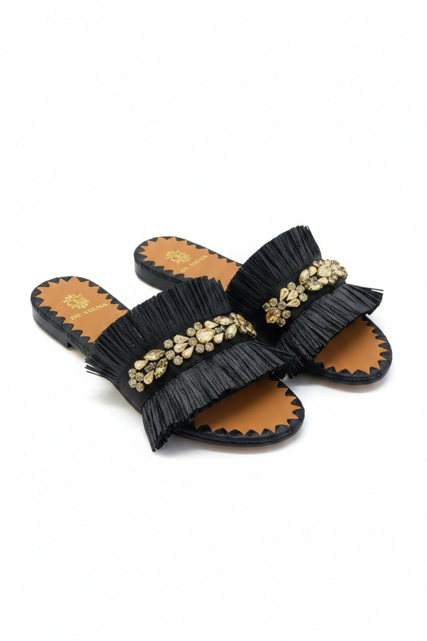 Add a touch of sparkle to any summer outfit with the DA SIENA - RAFFIA SLIDES WITH CRYSTALS by DE SIENA, featuring a tan sole, black ruffled strap, and gold jeweled embellishments atop the strap.