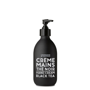 A sleek pump bottle of CIE LUXE BRANDS' COMPAGNIE DE PROVENCE - BLACK TEA HAND CREAM is infused with nourishing shea butter. The elegant white label displays "CREME MAINS LE NOIR HAND CREAM BLACK TEA" in French and English, offering a luxurious touch for your hands.