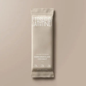 A STARS+HONEY - DARK CHOCOLATE COCONUT collagen protein bar is displayed on a coordinating beige background. The packaging emphasizes this low sugar protein bar from STARS+HONEY, highlighting that each bar contains 10g collagen, 13g protein, and only 2g sugar.