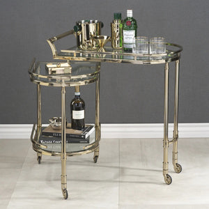 The SPIGA GOLD BAR CART by ZODAX features a vintage Italian-inspired design with elegant gold framing, mirrored glass shelves on both tiers, and smooth-rolling four-wheel mobility. Displayed against a white background, this piece is both stylish and functional.