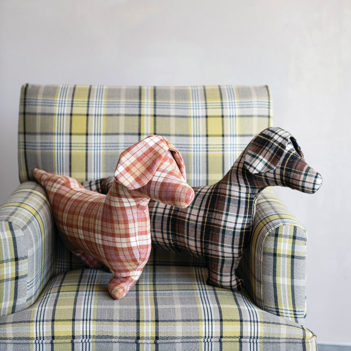 The CREATIVE COOP PLAID DOG-SHAPED PILLOWS, shown here in brown-green and red-orange patterns on a white background, bring cozy farmhouse style to any space.