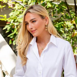 The CAPUCINE DE WULF - BERRY CLOVER STATION NECKLACE features a delicate 18K gold chain with handmade berry clover pendants, each displaying four round gold circles in a charming clover-like design.