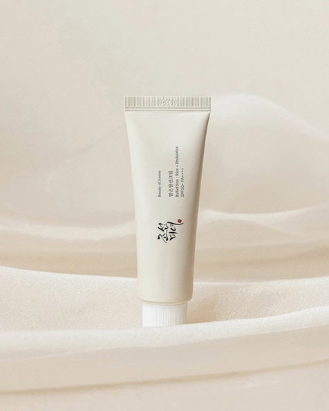 A white plastic tube with a white cap, featuring black and red Korean text on the front. This is the BEAUTY OF JOSEON - RELIEF SUN SUNSCREEN from KOSMIC KBEAUTY SKINCARE—a lightweight SPF50+ sunscreen, possibly formulated with rice extract, making it ideal for daily skincare routines.