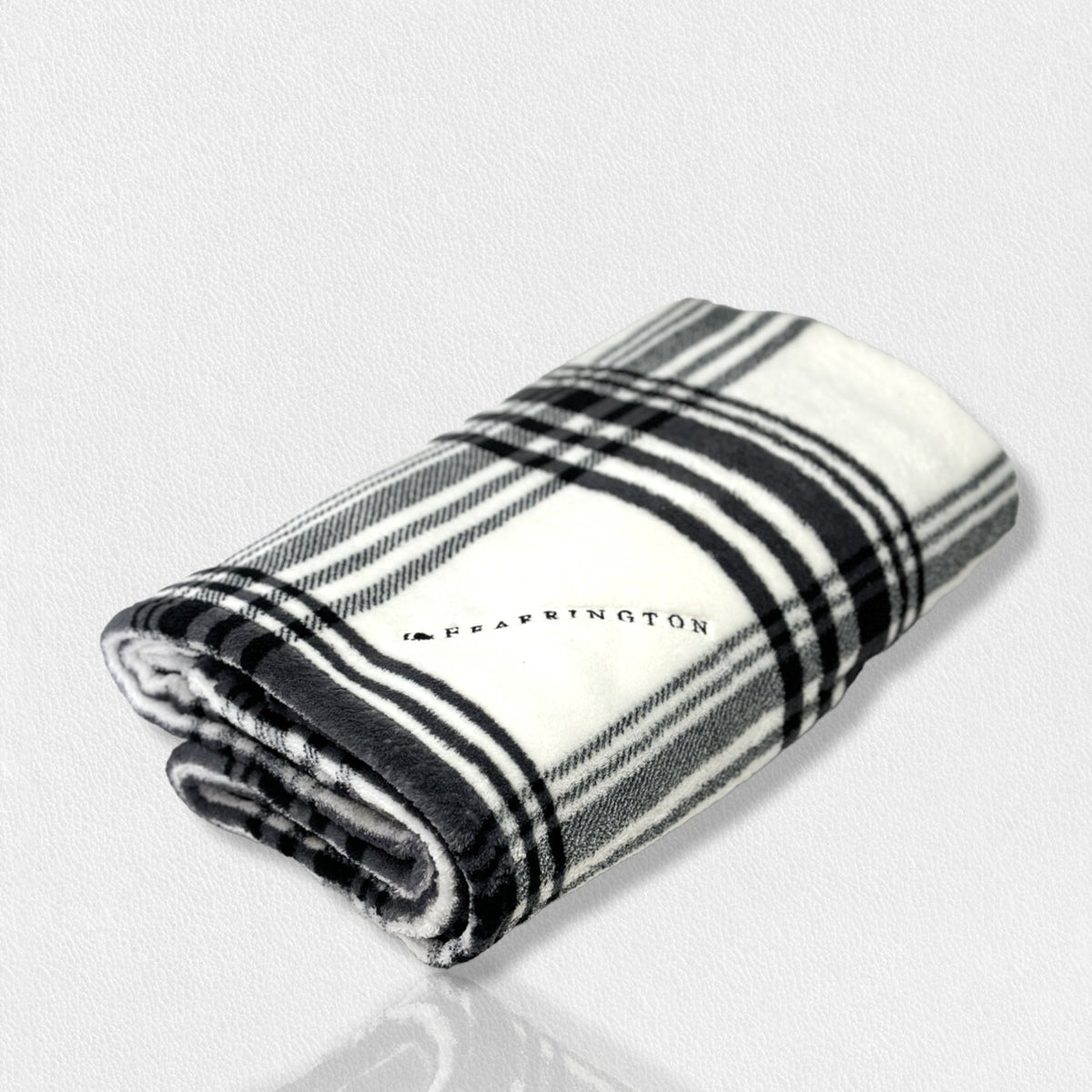 A folded, black-and-white plaid blanket from the FEARRINGTON SIGNATURE COLLECTION by STRAN PROMOTIONAL SOLUTIONS is displayed against a white background. The super-soft throw&#39;s sumptuous feel and classic pattern are prominently visible.