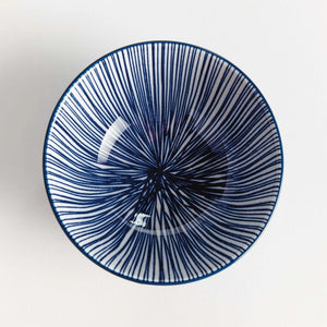 The NAPA HOME AND GARDEN - BLUE AND WHITE STRIA BOWL features a smooth blue exterior and an interior lined with thin vertical blue and white stripes for a modern look.