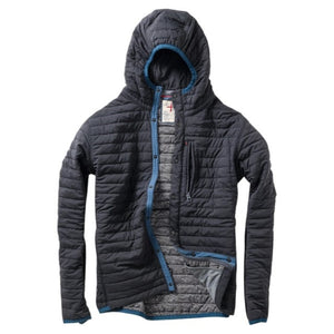 Wearing the RELWEN - WINDZIP HOOD IN BLACK FADE, a black water-resistant jacket with recycled polyester insulation from RELWEN, a person stands on a snowy path in blue pants, covering their face with their hand. Snow falls gently as snow-laden trees fill the background.